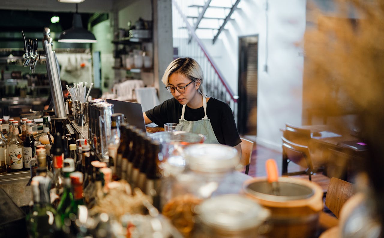 Young concentrated Asian female bartender working at counter